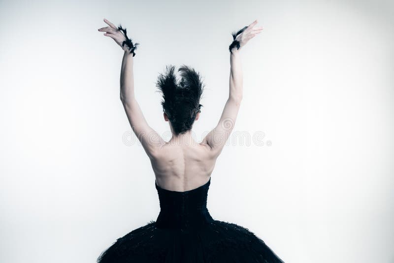 Back view of young ballerina wearing black tutu, stage dress posing  on white studio backgorund