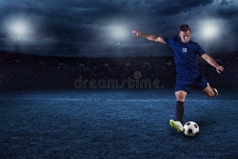 Gracza piłki nożnej kopania piłka w wielkim stadium przy nocą fotografia royalty free Gracza piłki nożnej kopania piłka w wielkim stadium przy nocą fotografia royalty free
