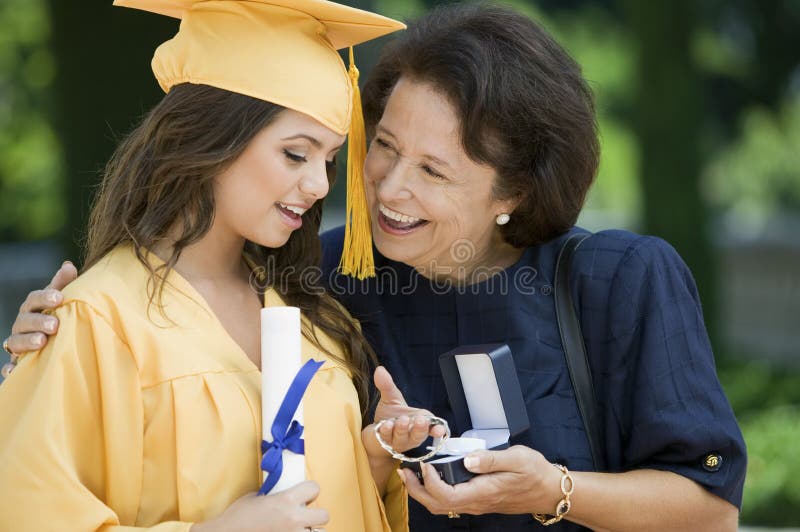 Graduate Receiving bracelet from Grandmother outside stock photo Graduate Receiving bracelet from Grandmother outside stock photo