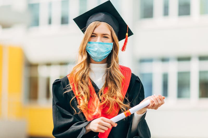A graduate student in a medical mask, in a black graduation dress, with a diploma in her hands. Graduation ceremony concept, royalty free stock photography A graduate student in a medical mask, in a black graduation dress, with a diploma in her hands. Graduation ceremony concept, royalty free stock photography