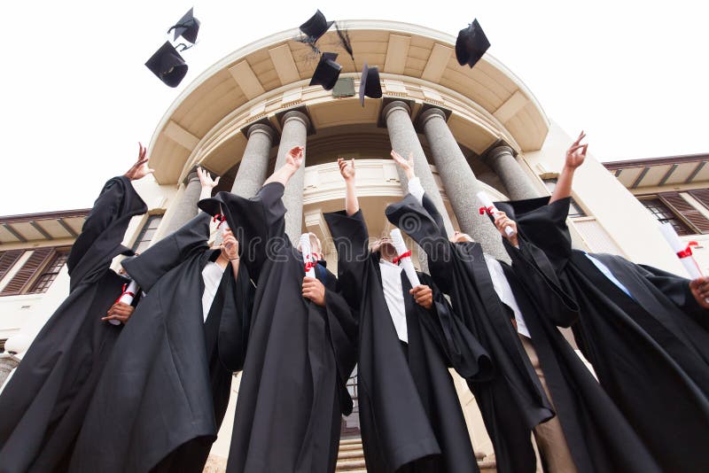 Group of happy graduates throwing graduation hats in the air celebrating. Group of happy graduates throwing graduation hats in the air celebrating