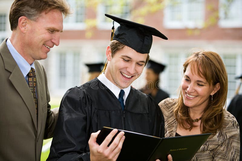 Graduazione: La famiglia fiera ammira il diploma fotografia stock libera da diritti Graduazione: La famiglia fiera ammira il diploma fotografia stock libera da diritti