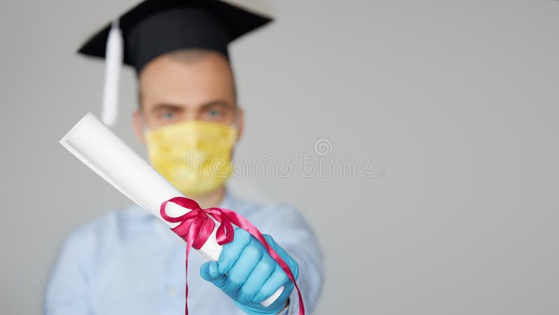 High school graduation during a quarantine. Student graduate in a hat and a protective mask holds a diploma. High school graduation during a quarantine. Student graduate in a hat and a protective mask holds a diploma