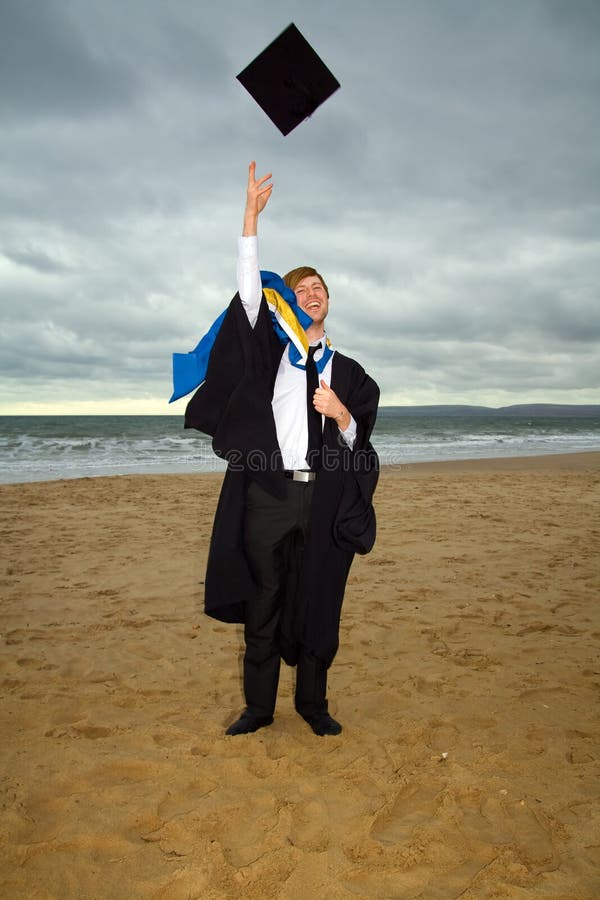 Student in cap and gown or ropes. graduate from university celebrating degree by throwing hat. male on the beach by sea. Student in cap and gown or ropes. graduate from university celebrating degree by throwing hat. male on the beach by sea