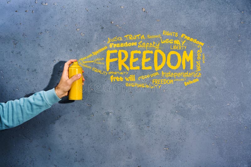 Graffiti Painter with Spray Paint in His Hands Draws the Word FREEDOM and Synonyms on Concrete
