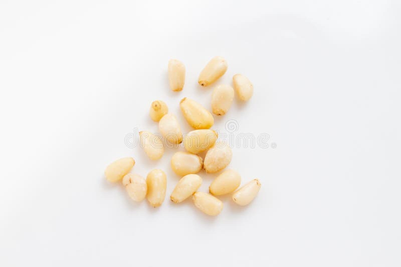Grains of peeled pine nuts on a white background stock photo