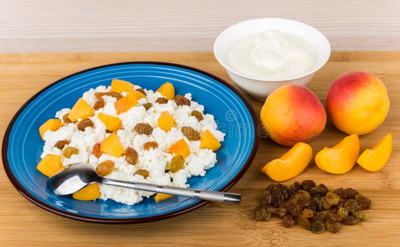 Grainy curd with peaches and raisins, bowl with sour cream stock image