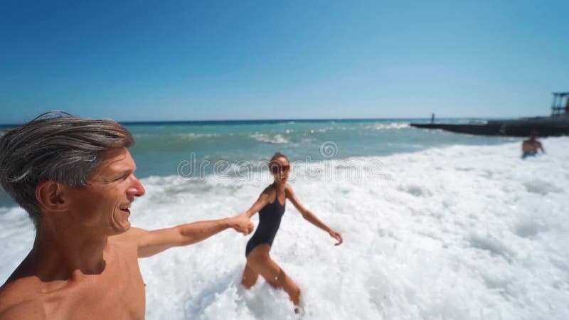 Gran angular lento movimiento feliz pareja de manos con alegres caminatas en la playa de mar agitando almacen de video