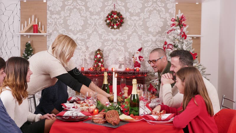Gran familia reunida alrededor de la mesa de Navidad disfrutando de comida tradicional metrajes