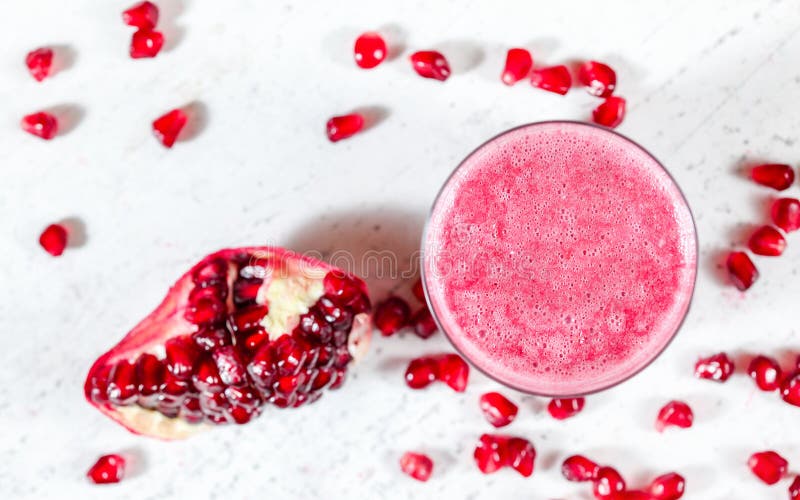 Granatowa smoothie z zamazanym klejnotem lubi owoc rozprasza blisko na białej desce Fotografia z góry, ostrość na bąblach we fotografia stock Granatowa smoothie z zamazanym klejnotem lubi owoc rozprasza blisko na białej desce Fotografia z góry, ostrość na bąblach we fotografia stock