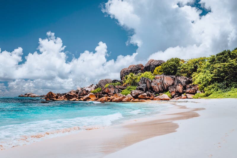 Grand Anse tropical beach in La Digue, Seychelles. Famous granite rock formations and white clouds above