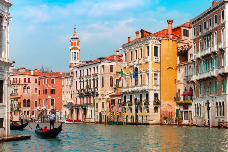 Gondolier carries tourists on Traditional gondola along Grand Canal in summer sunny day, Venice, Italy. Gondolier carries tourists on Traditional gondola along Grand Canal in summer sunny day, Venice, Italy