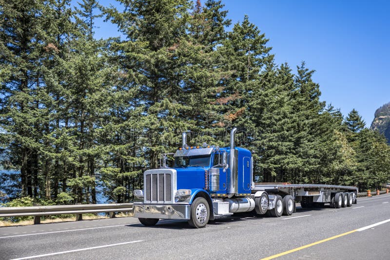 Grand classique bleu gros camion semi truck avec protection de grille  pare-choc et couverts chargement sur remorque à plateau en bois pont à  travers la rivière Columbia Photo Stock - Alamy