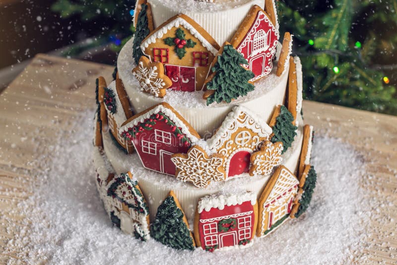 Grand gâteau à gradins de Noël décoré des biscuits de pain d'épice et une maison sur le dessus Arbre et guirlandes à l'arrière-pl photo libre de droits Grand gâteau à gradins de Noël décoré des biscuits de pain d'épice et une maison sur le dessus Arbre et guirlandes à l'arrière-pl photo libre de droits
