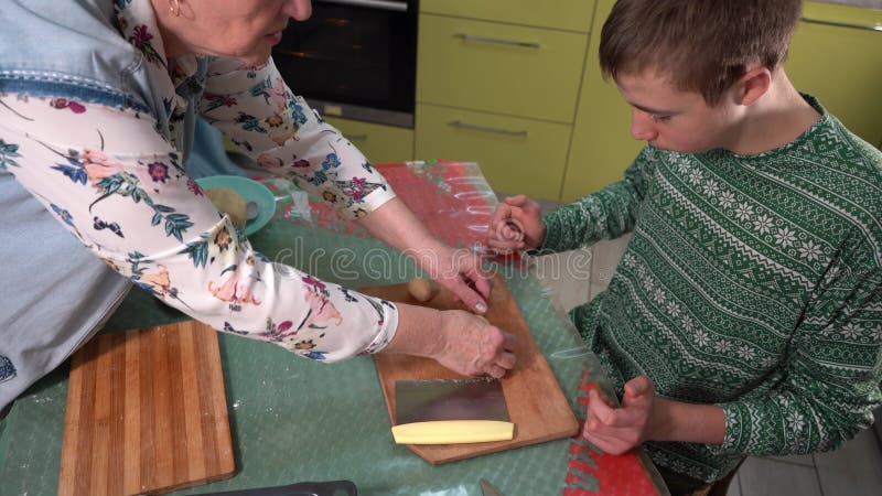 Grand-mère enseigne à petit-fils à faire des biscuits à partir de pâte. Cuire à la maison. Cuisson sur table. Vue supérieure des m clips vidéos