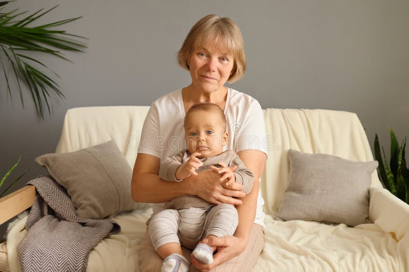 Grand-mère et petit-fils souriants qui passent du temps ensemble assis sur un canapé à la maison et passent du temps en famille pe photographie stock