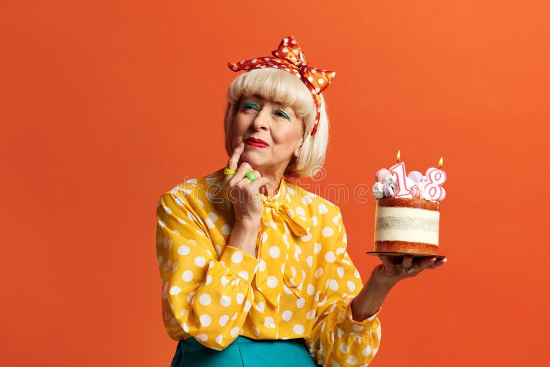 Grand-mère méditation célébrant l'anniversaire. dame tient le gâteau avec des bougies en feu photo libre de droits