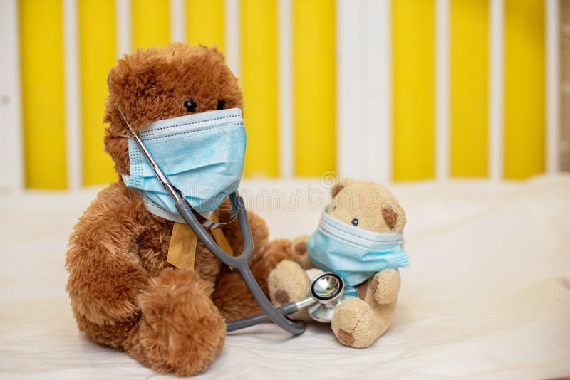 Bébé Dans Un Masque Médical Joue Avec Un Ours En Peluche. Bébé