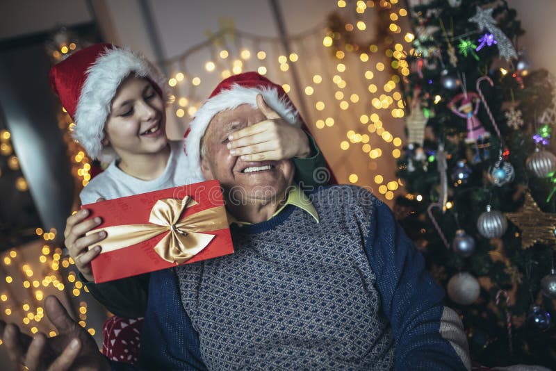 Grand-père et petit-fils assis sur la chaise avec des cadeaux pendant noël photographie stock