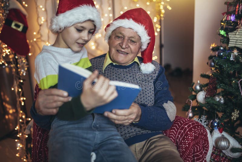Grand-père et petit-fils assis sur le fauteuil et le livre de lecture pendant noël photos libres de droits