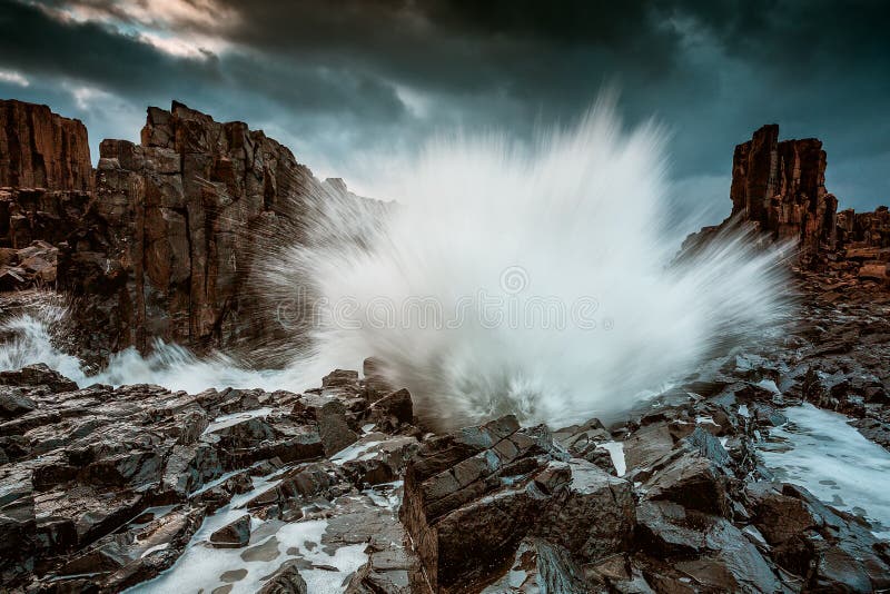 Grand spash de vague massive aux colonnes de basalte de Bombo image stock Grand spash de vague massive aux colonnes de basalte de Bombo image stock