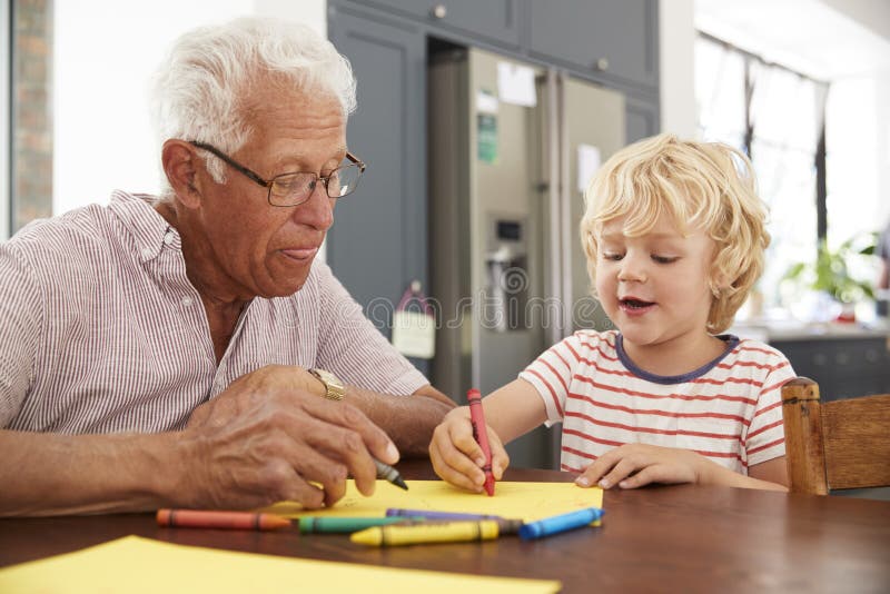 Grandad and grandson drawing together in family kitchen, close up