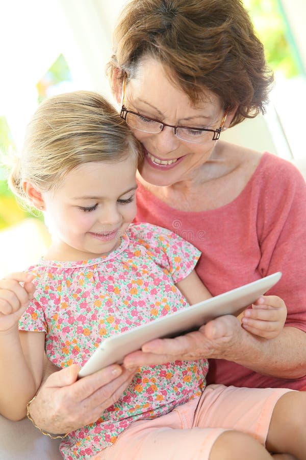 Granddaughter and grandmother playing together on a tablet