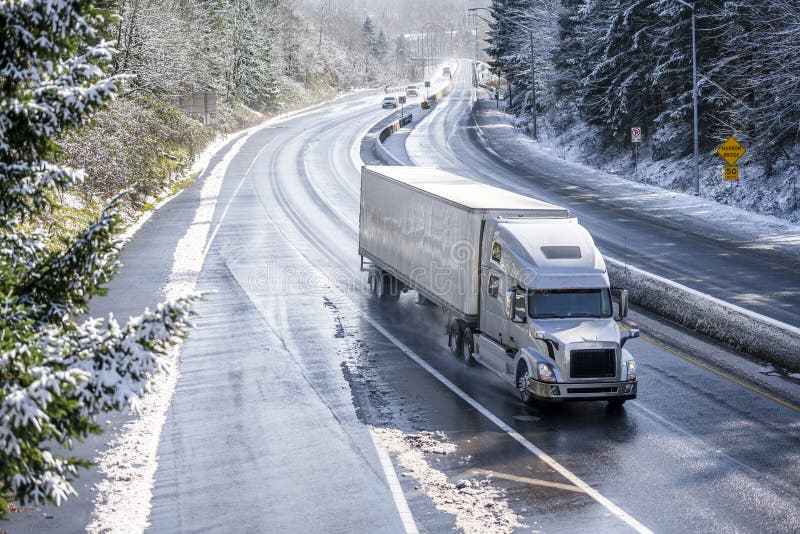 Grande camion dei semi dell'impianto di perforazione con il rimorchio dei semi che guida sulla strada principale nevosa di invern fotografie stock