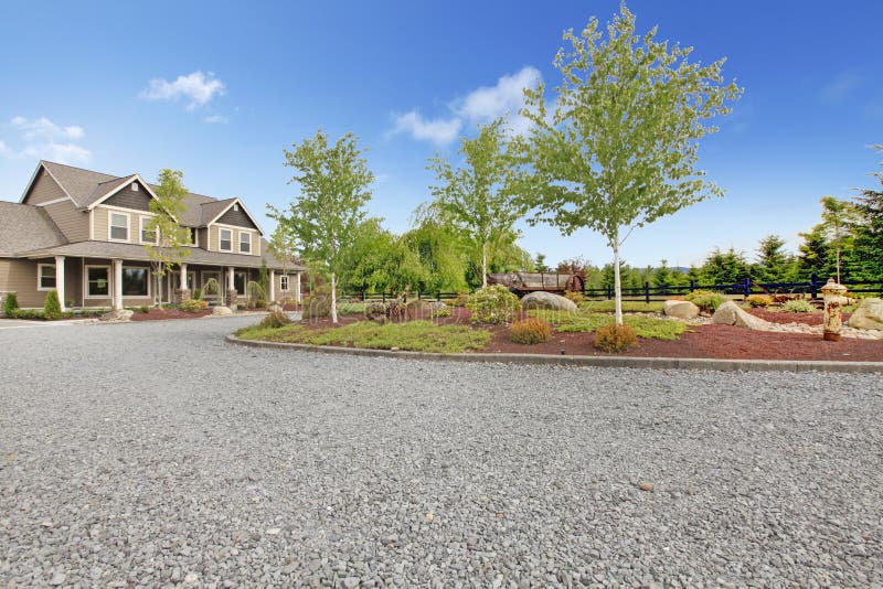 Large brown farm country house with gravel driveway and green landscape. Large brown farm country house with gravel driveway and green landscape.