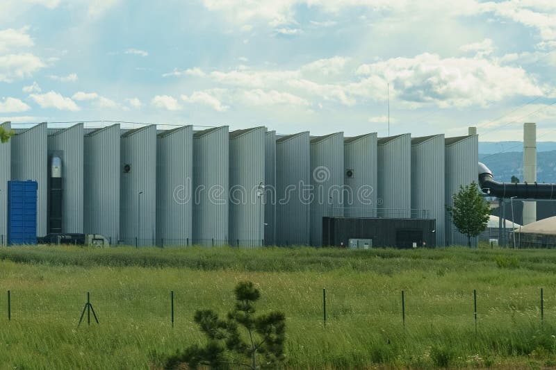 A substantial building stands prominently amidst a vibrant green field, showcasing a stark contrast between man-made structure and natural surroundings. A substantial building stands prominently amidst a vibrant green field, showcasing a stark contrast between man-made structure and natural surroundings.