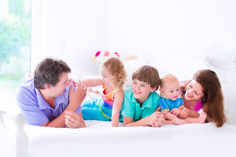 Grande famiglia felice in un letto fotografia stock Grande famiglia felice in un letto fotografia stock
