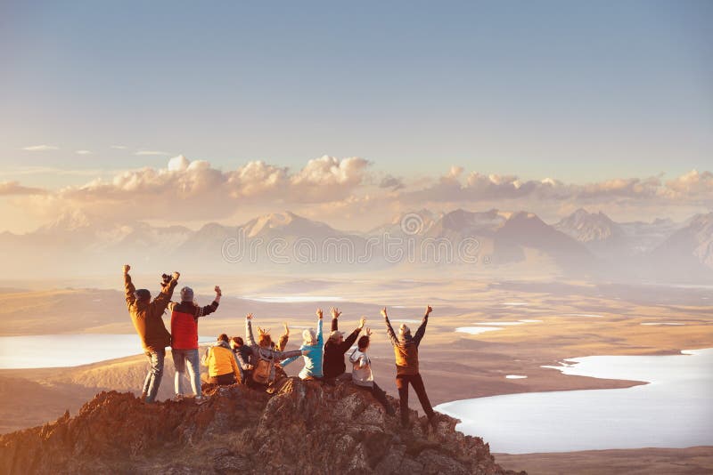 Large group of happy friends is having fun on mountain top and looks at mountain`s valley. Adventure or travel concept. Large group of happy friends is having fun on mountain top and looks at mountain`s valley. Adventure or travel concept