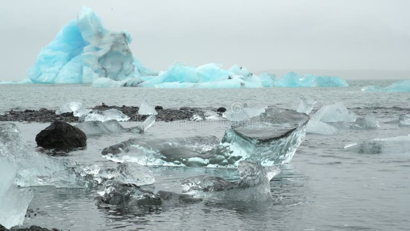 Grande pedaço de gelo e icebergue azul puro na praia de areia negra na islândia 8k 4 2 2 10 bits (log classificado)