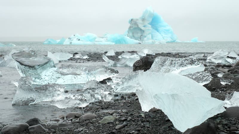 Grande pedaço de gelo e icebergue azul puro na praia de areia negra na islândia 8k 4 2 2 10 bits (log classificado)