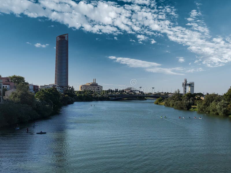 Grande rivière avec des gens faisant la course en kayaks belle vue sur la ville avec des bâtiments modernes. Vue détaillée de la ville avec des bâtiments modernes avec de nombreuses reflets