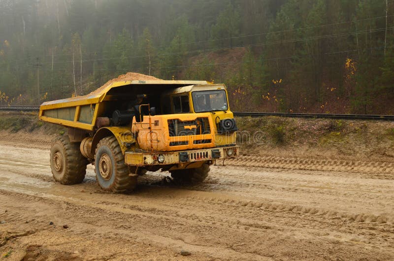 Grande scaricatore diesel giallo della cava sul lavoro Carrello di miniera pesante che trasporta sabbia ed argilla fotografia stock Grande scaricatore diesel giallo della cava sul lavoro Carrello di miniera pesante che trasporta sabbia ed argilla fotografia stock