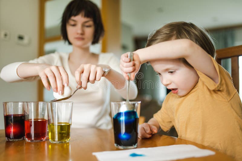 Grande soeur et son petit frère qui teignent les oeufs de Pâques à la maison. Enfants peignant des oeufs colorés pour la chasse de images stock