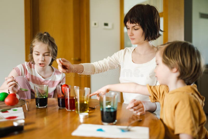 Grande soeur et son petit frère qui teignent les oeufs de Pâques à la maison. Enfants peignant des oeufs colorés pour la chasse de photo stock