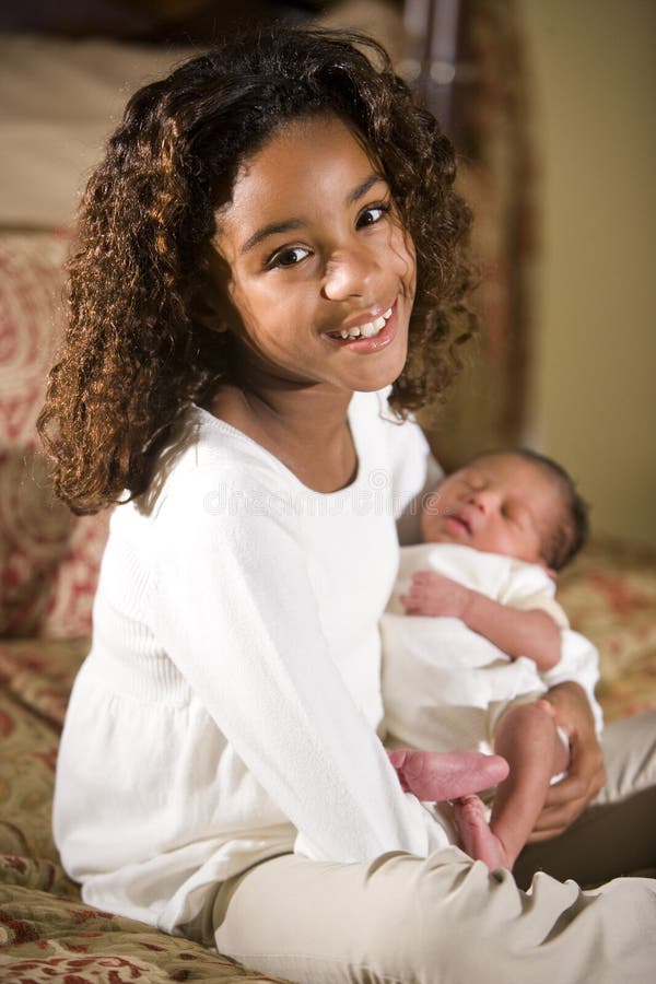 Grande soeur retenant l'enfant de mêmes parents nouveau-né photographie stock libre de droits Grande soeur retenant l'enfant de mêmes parents nouveau-né photographie stock libre de droits