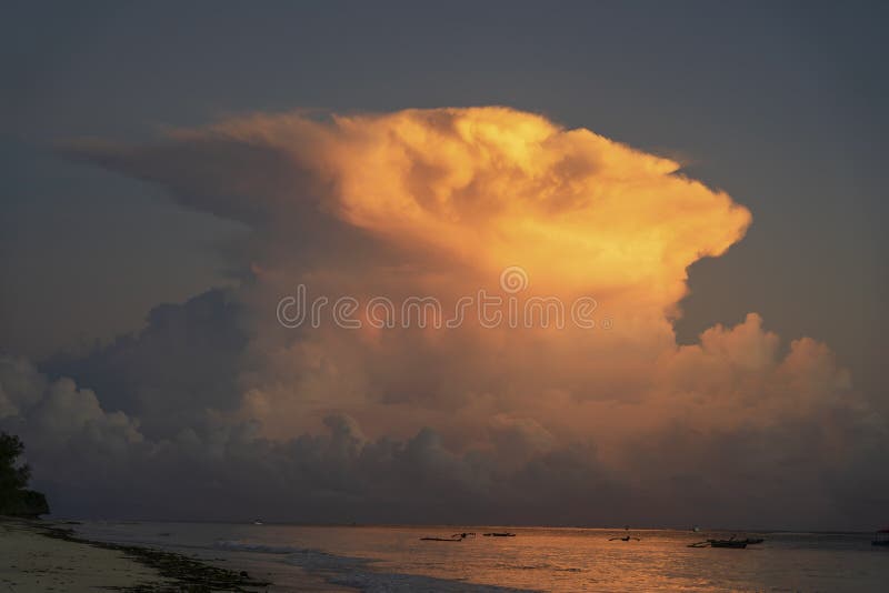 Big white clouds and sky over sea water on tropical beach during sunrise on the island of Zanzibar, Tanzania, East Africa. Travel and nature concept. Big white clouds and sky over sea water on tropical beach during sunrise on the island of Zanzibar, Tanzania, East Africa. Travel and nature concept