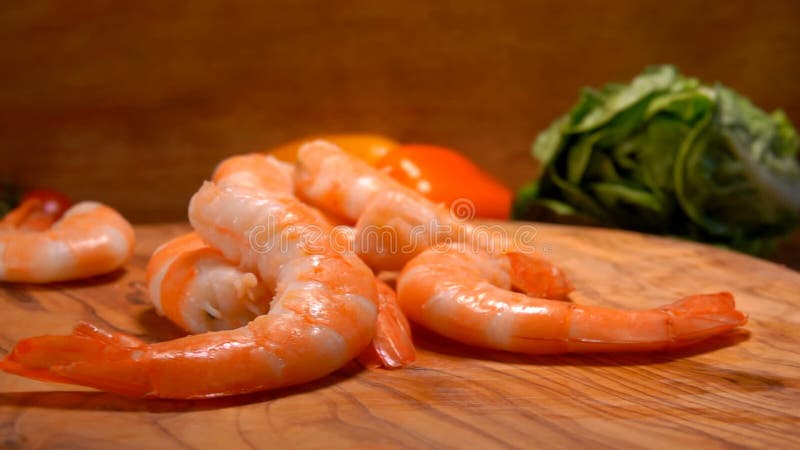 Grandes y deliciosas gambas caen sobre la tabla de madera