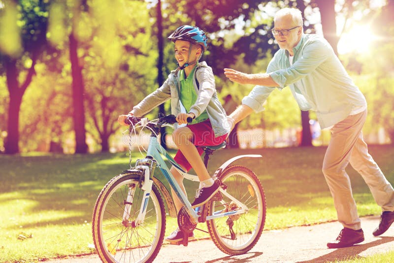 Grandfather and boy with bicycle at summer park