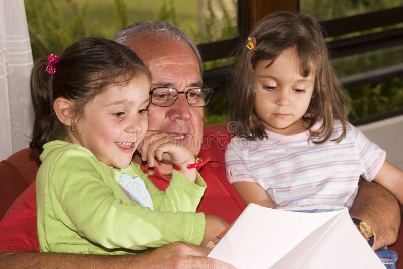 Grandfather and granddaughters reading together royalty free stock photos