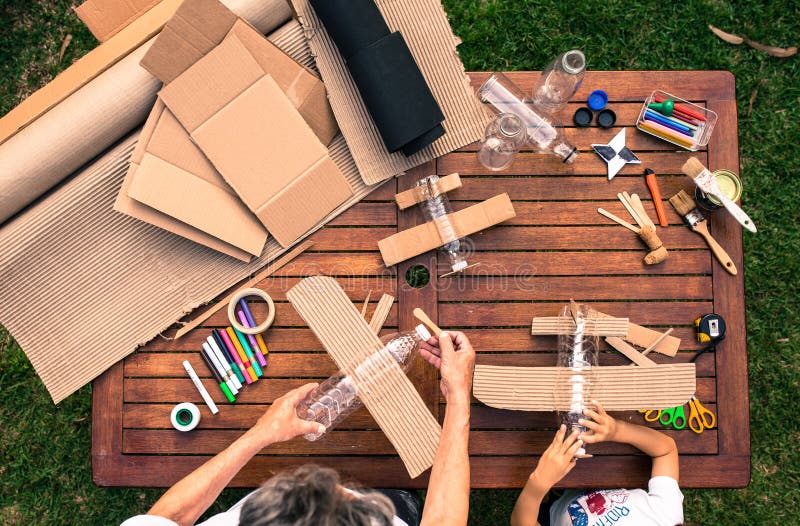 Grandfather and grandson building airplanes with recycled material cardboard, PVC bottles, wood. work ideas circular economy, re