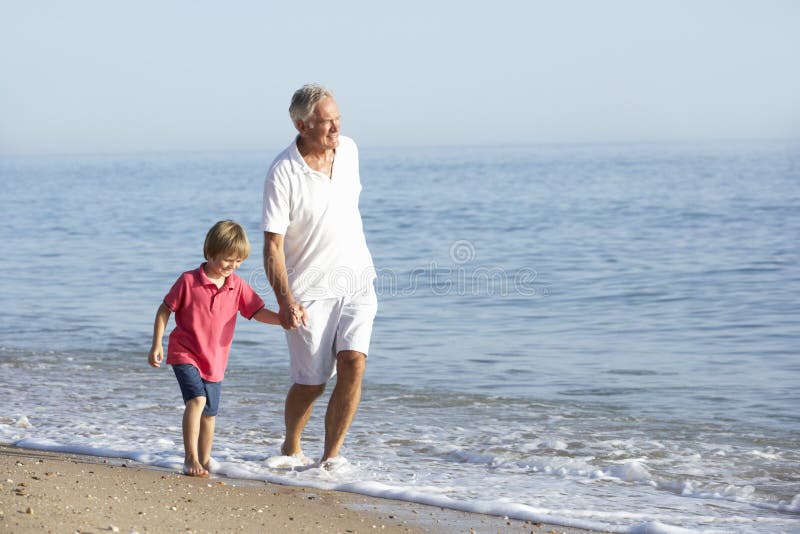 Grandfather And Grandson Enjoying Walk Along Beach