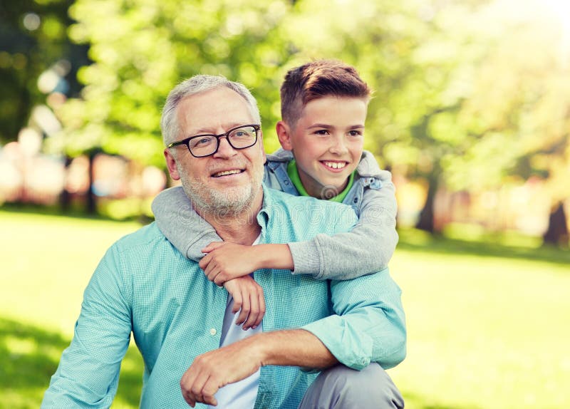 Grandfather and grandson hugging at summer park. 