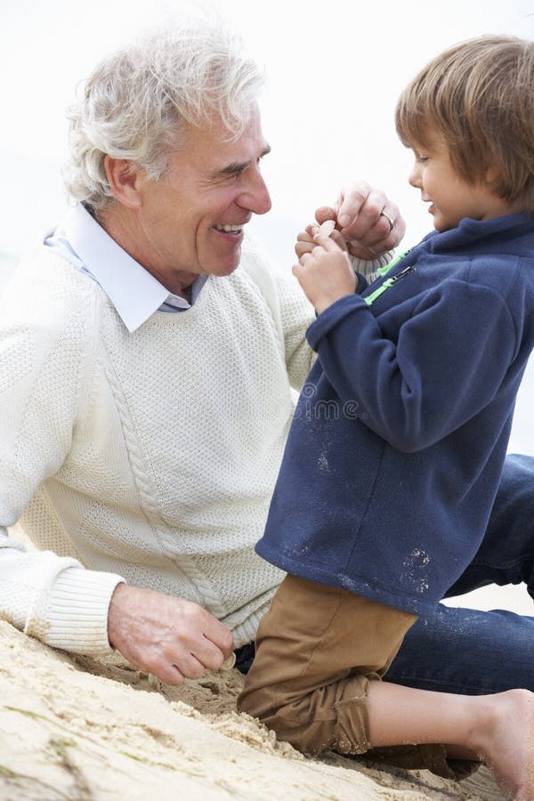 Grandfather And Grandson Looking at Shell On Beach Together royalty free stock image Grandfather And Grandson Looking at Shell On Beach Together royalty free stock image