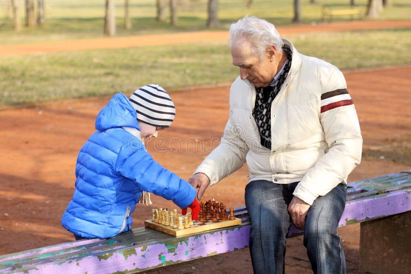 Дед с внуком играют в шашки. Дед и внук на скамейке. Дедушка с внуками на скамейке. Дед на соревновании. Дедушка играет с внуками.