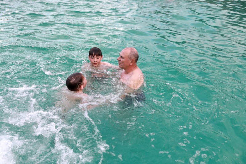 Grandfather and grandsons swimming in warm thermal pool royalty free stock photography