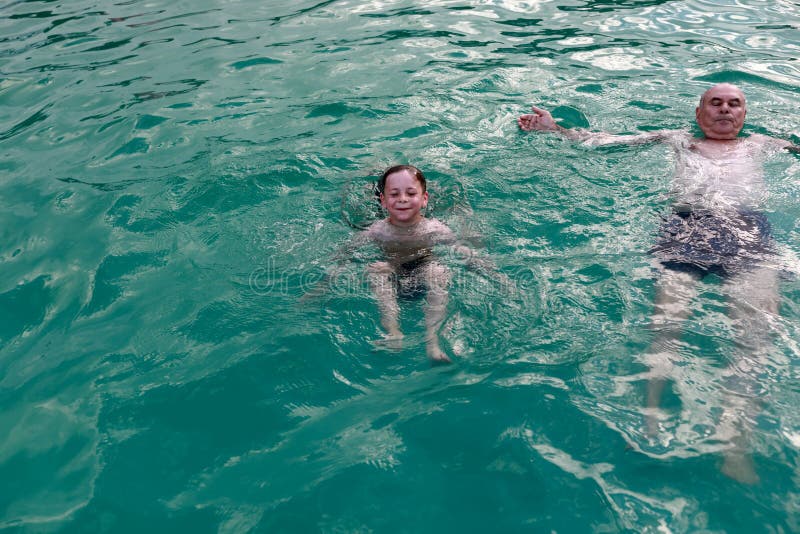 Grandfather with his grandson swimming in pool royalty free stock images